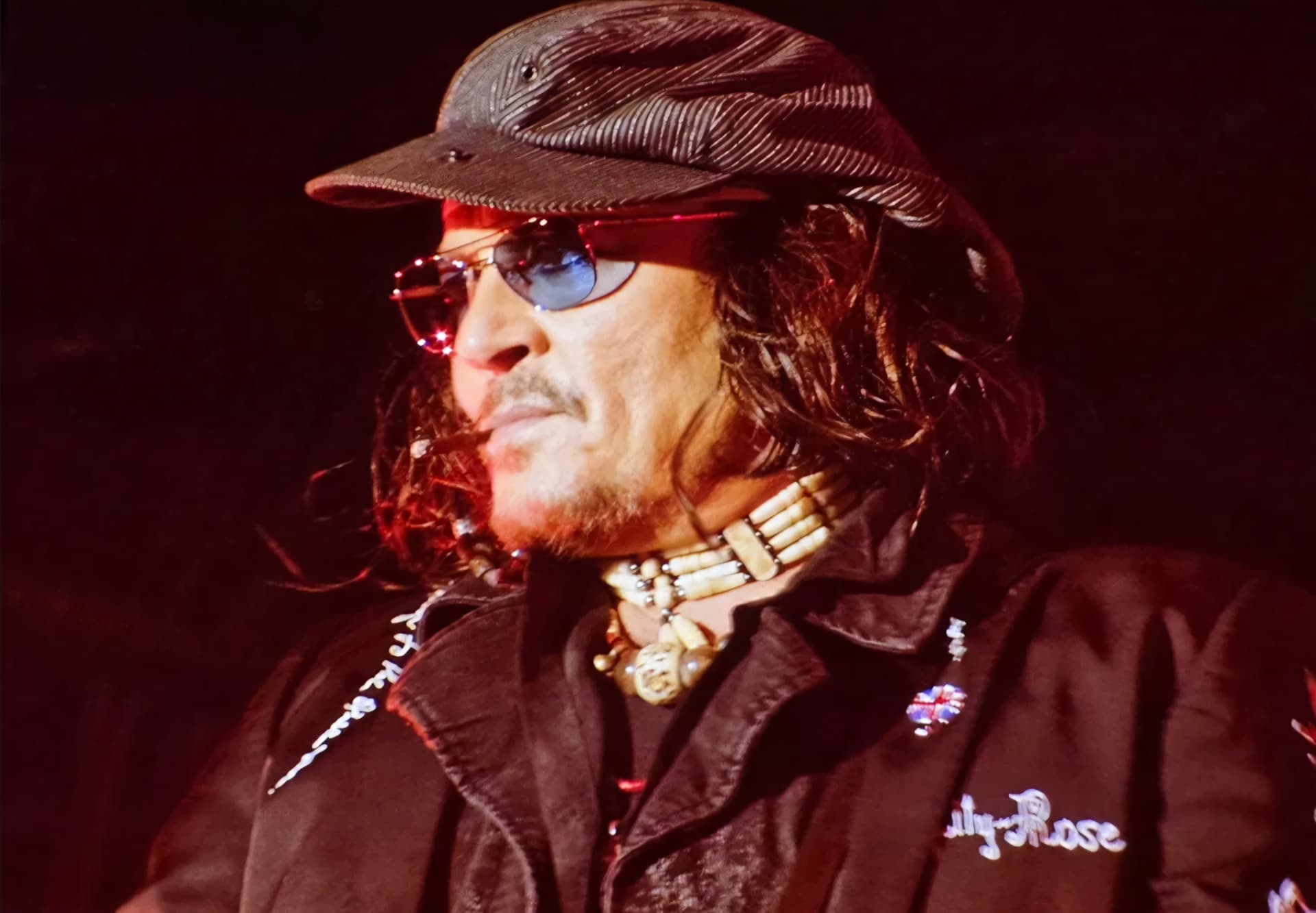 Johnny Depp on the venue screen, in cap and tinted glasses