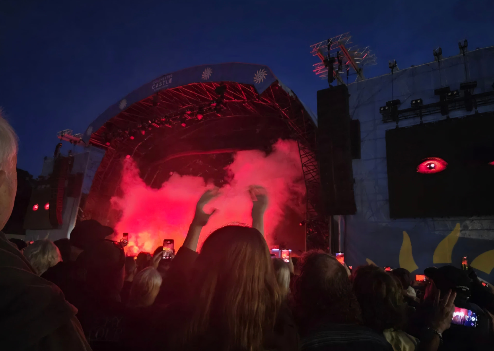 Red smoke across the Castle Park stage at dusk, phones raised in the crowd